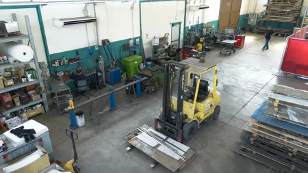 Interno dell'officina di carpenteria metallica Lyco con muletto e banchi di lavoro