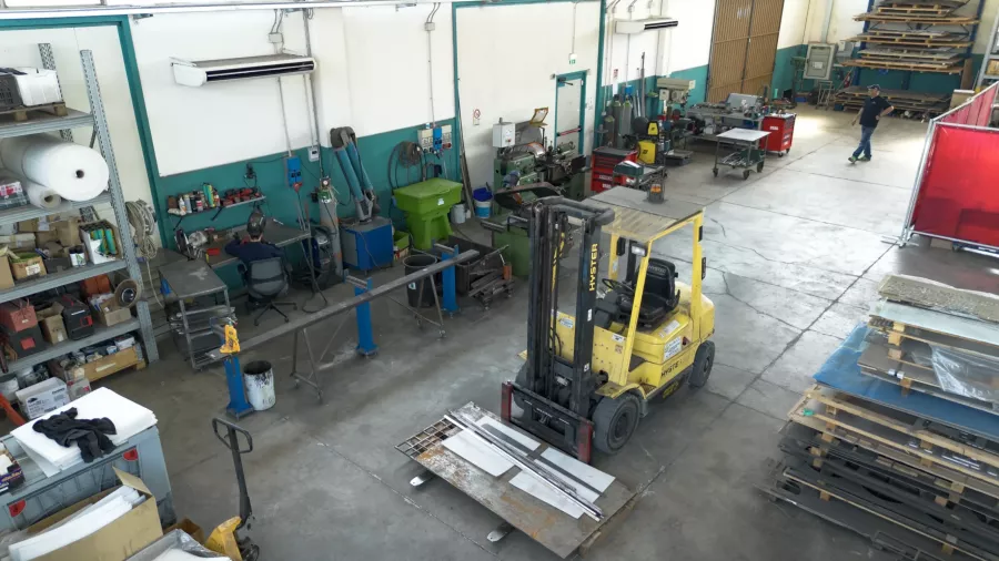 Interno dell'officina di carpenteria metallica Lyco con muletto e banchi di lavoro